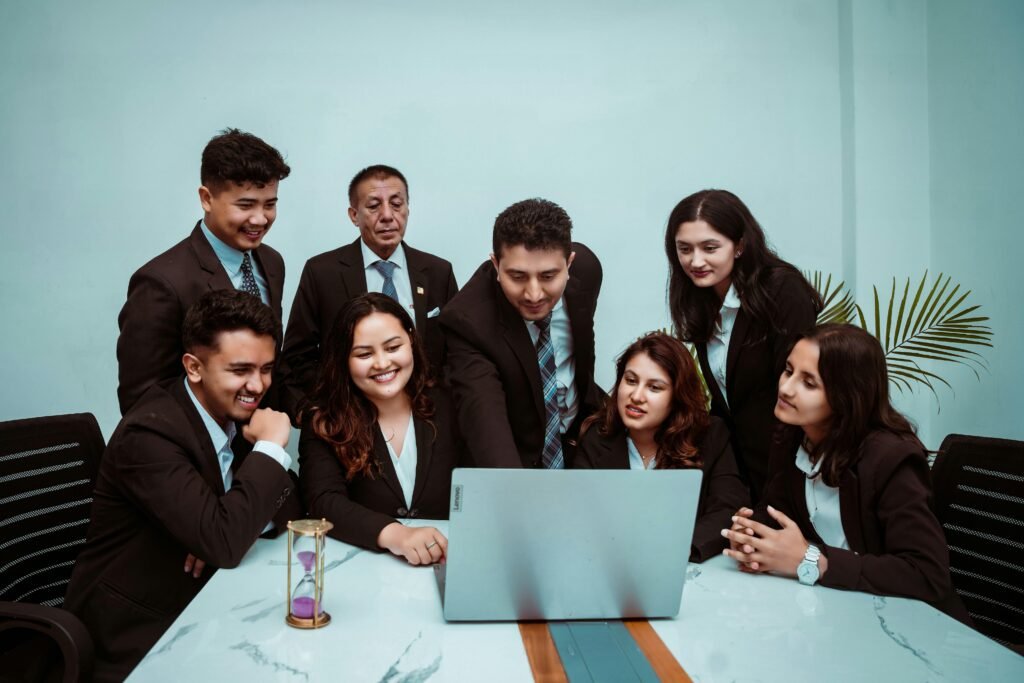 A diverse team of professionals collaborating around a laptop in a modern office setting.